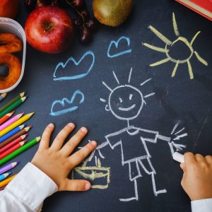 childrens hands writing on a blackboard. school concept. the toning. selective focus